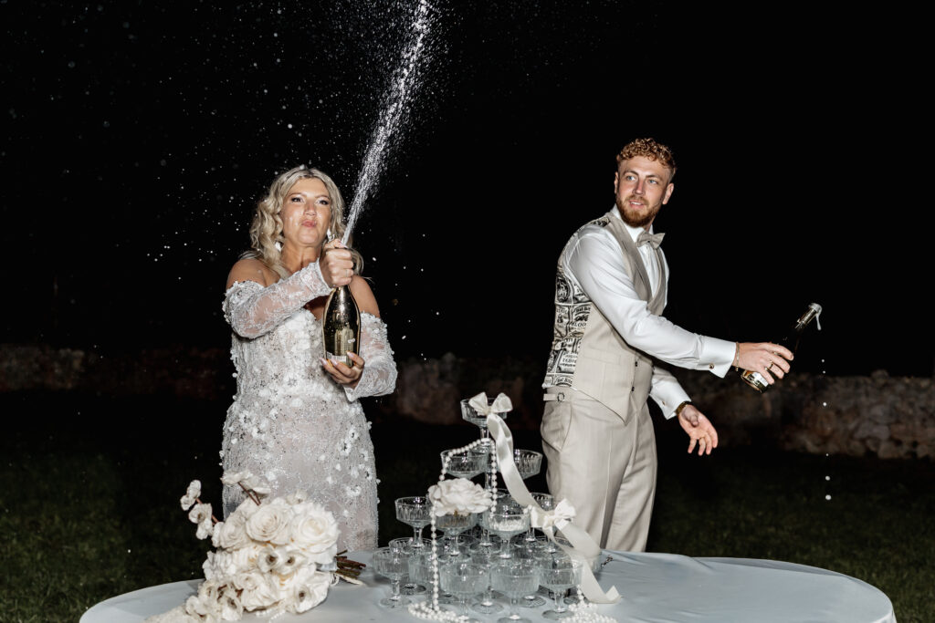 Braut und Bräutigam lachen beim Sekt spritzen am Sektturm