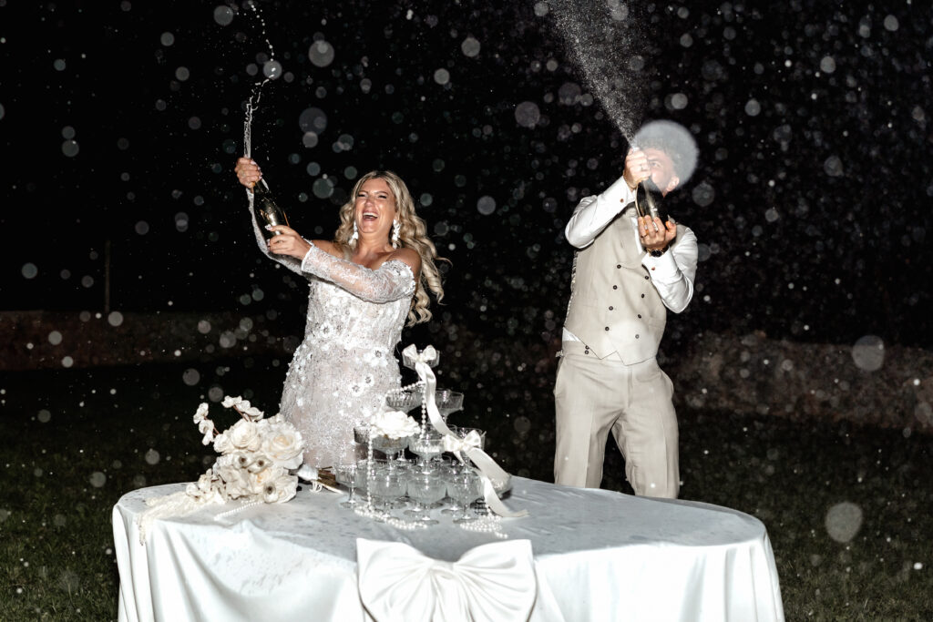 Braut und Bräutigam eröffnen den Sektturm bei Hochzeit am Abend