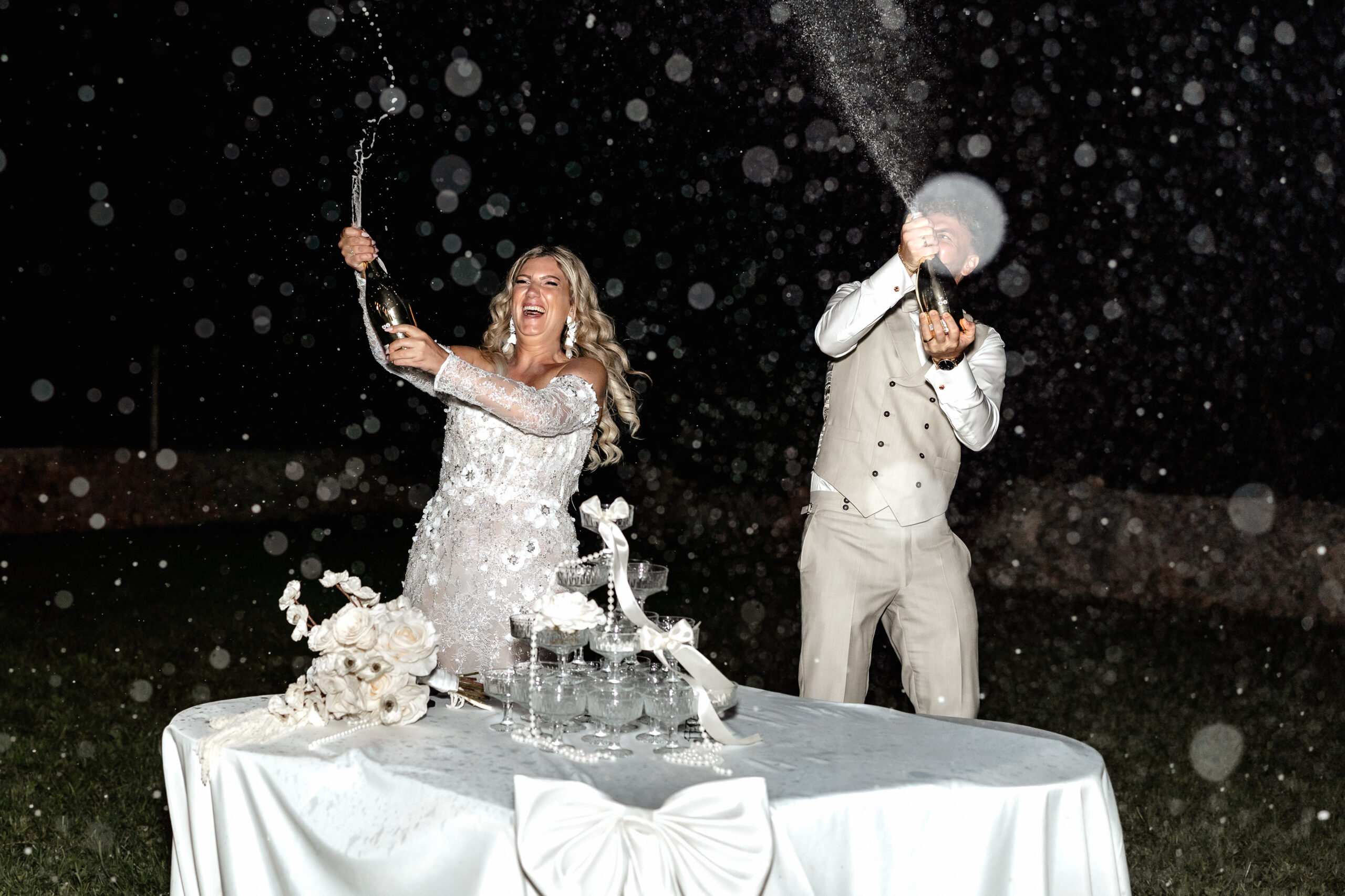 Braut und Bräutigam eröffnen den Sektturm bei Hochzeit am Abend