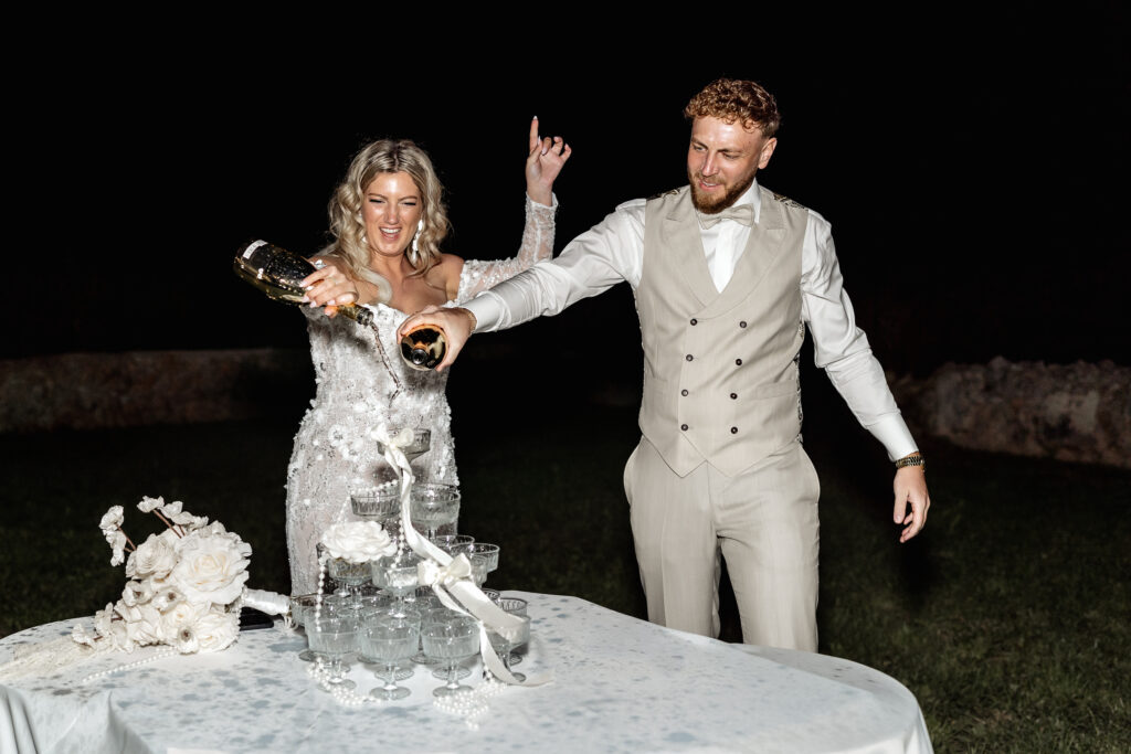 Braut und Bräutigam schenken Sekt in den Sektturm ein