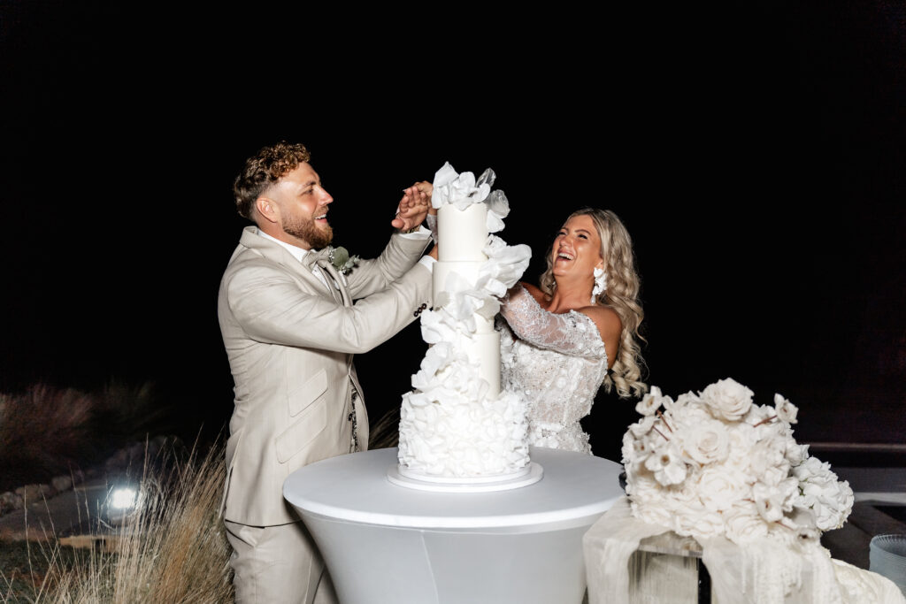 Brautpaar lacht beim Anschneiden der Hochzeitstorte auf Mallorca