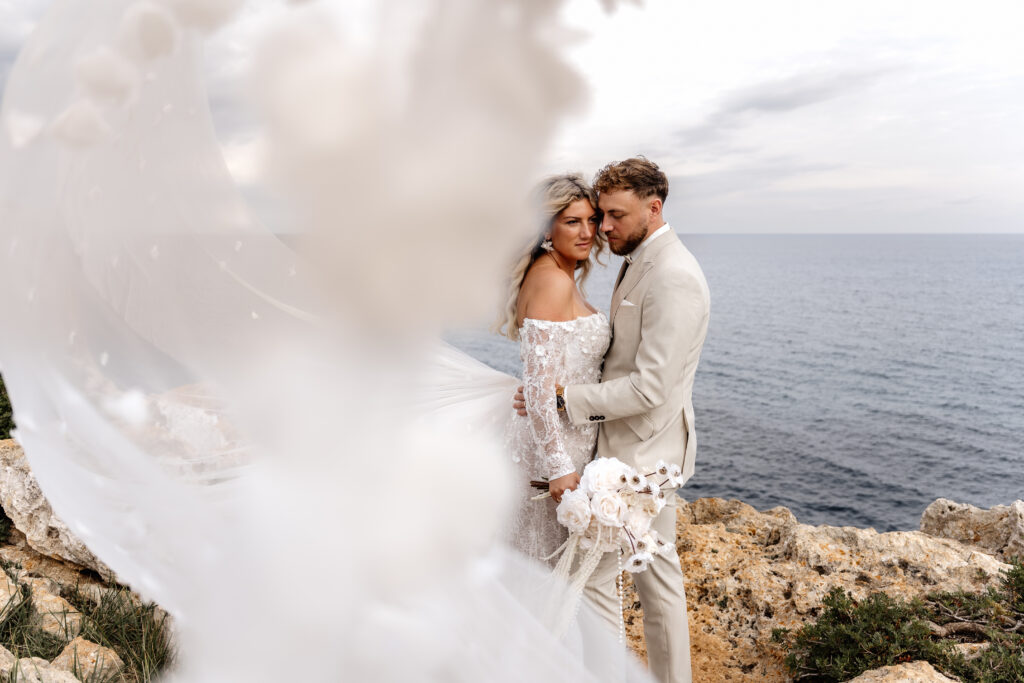 Brautschleier weht im Wind bei After-Wedding-Shooting auf Klippen Mallorca